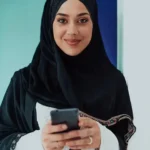 a woman wearing a black head scarf holding a phone